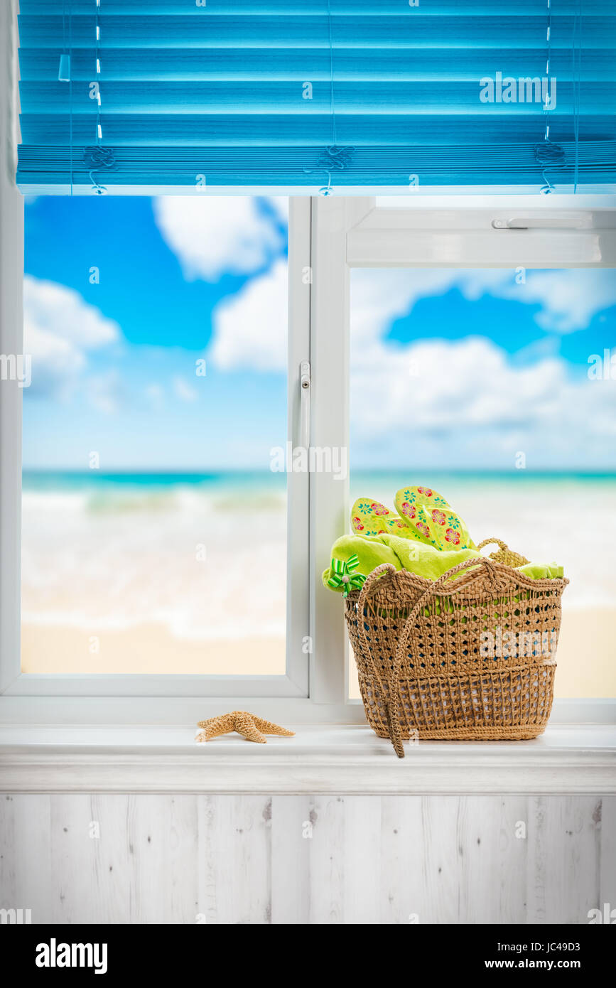 Panier de plage rempli de serviette et des tongs dans la fenêtre Banque D'Images