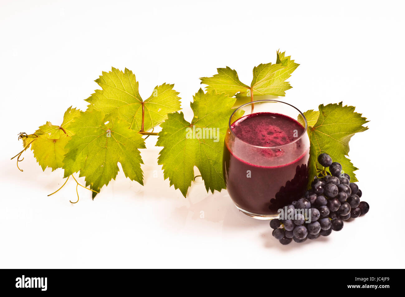 Gepresster roter Traubensaft frisch auf Weinlaub mit weißem Hintergrund Banque D'Images