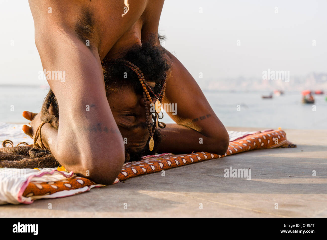 Un sadhu, saint homme, est la pratique du yoga asana sur une plate-forme à la sainte gange à meer ghat à la banlieue, godowlia Banque D'Images