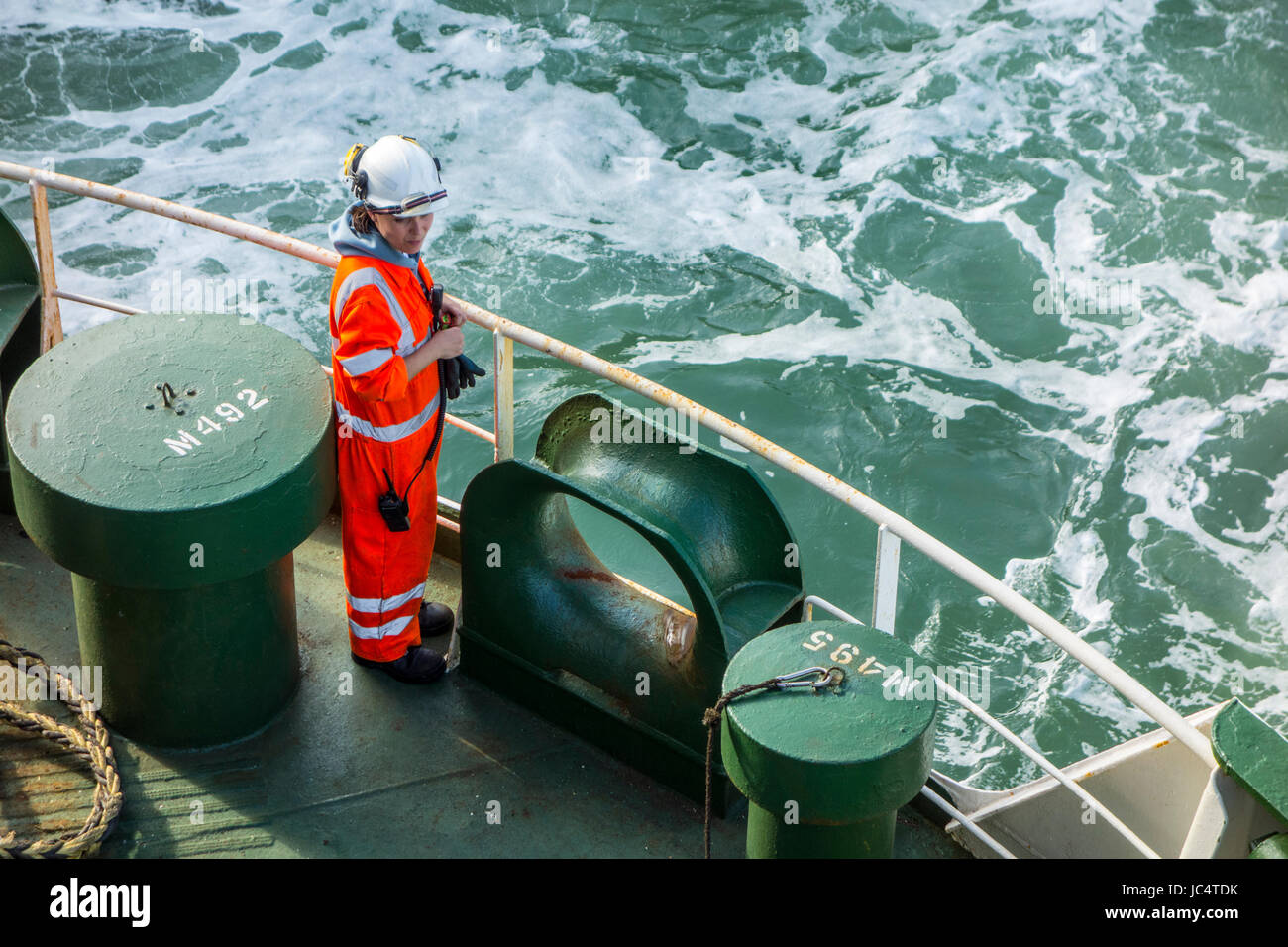 Membre de l'équipage féminin en orange dans l'ensemble et de porter un casque de sécurité travaillent sur le pont du cargo transporteur de voiture / en mer Banque D'Images