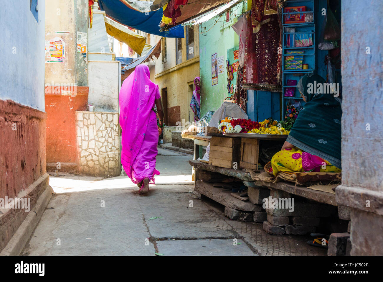 Une femme, vêtue d'un sari rose, marche dans les rues de la banlieue godowlia Banque D'Images
