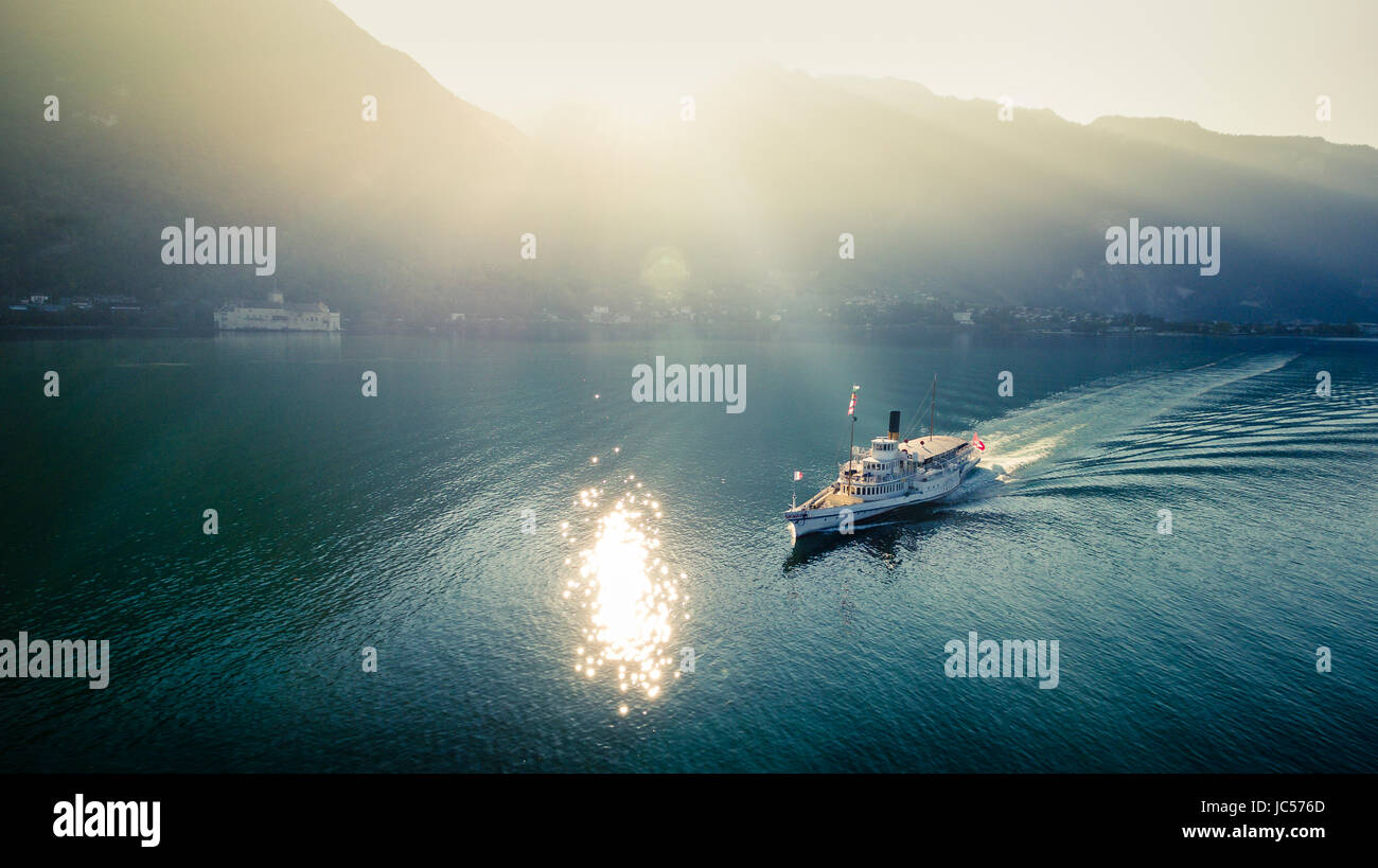Croisière en bateau sur le lac Léman au coucher du soleil, le soleil se reflétant dans les eaux et avec des montagnes en arrière-plan dans le Canton de Vaud, Suisse Banque D'Images