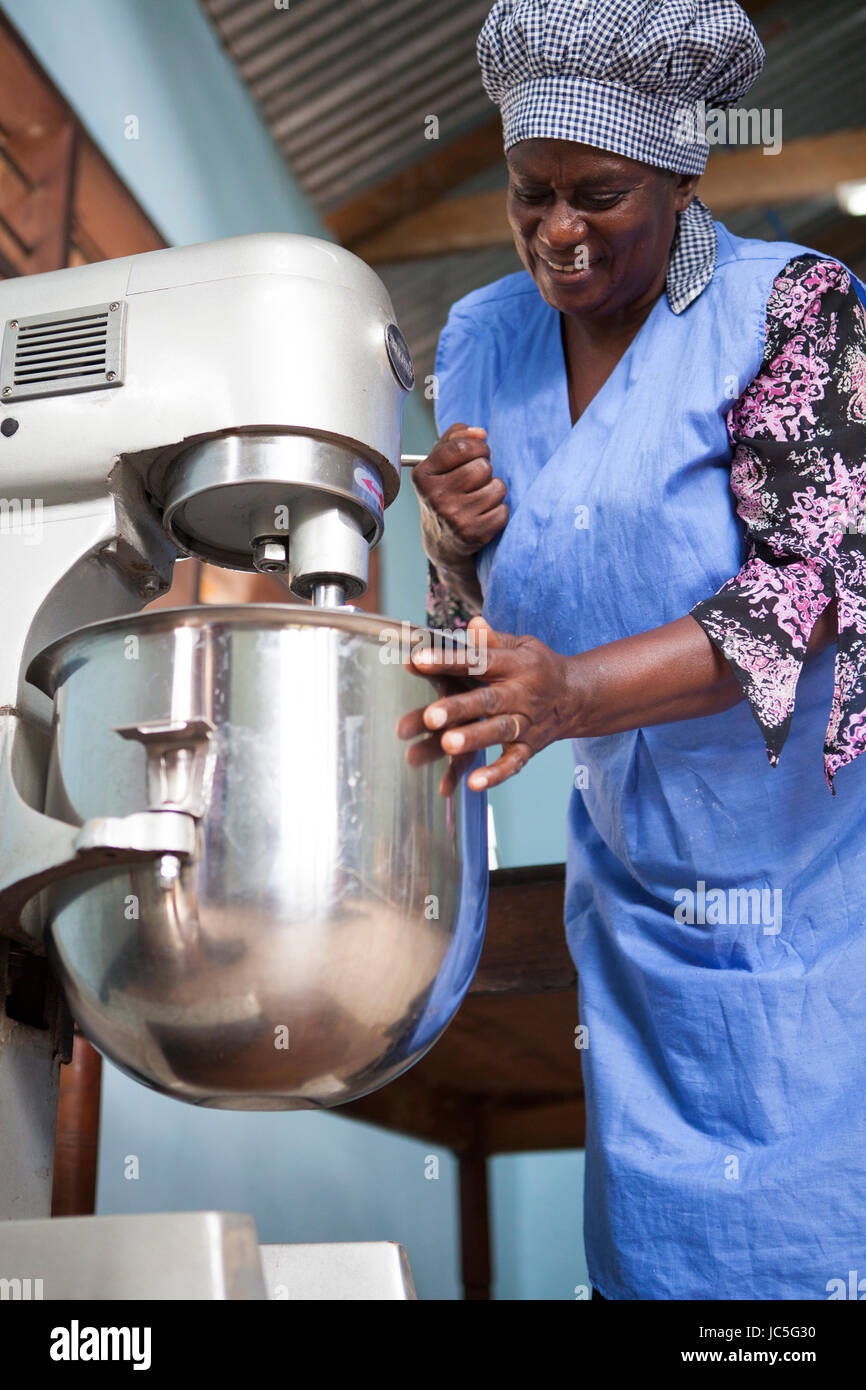 Une femelle Baker en utilisant son mixeur pour faire du pain. La Tanzanie, Afrique. Banque D'Images