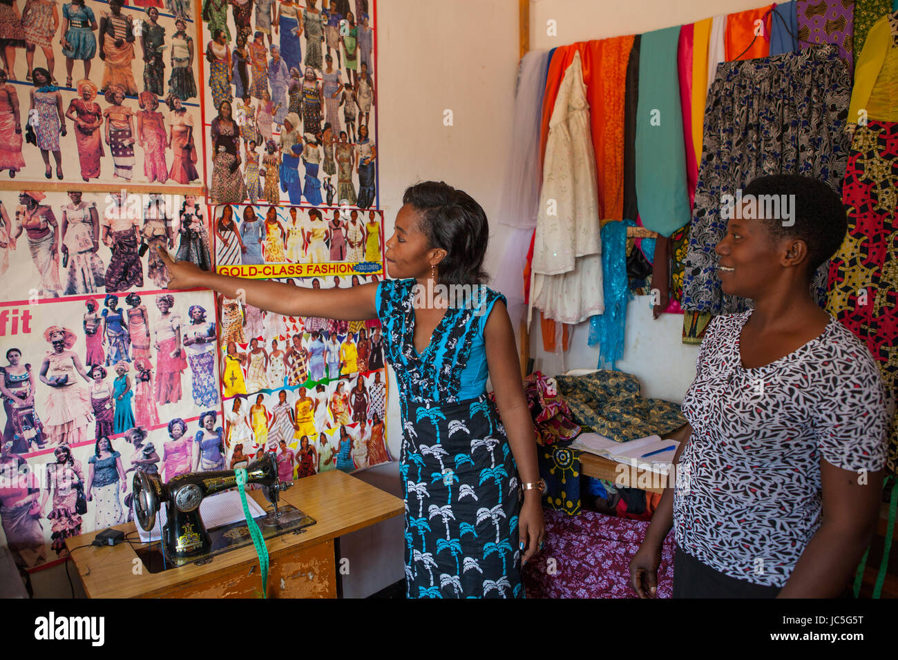 Une femme sur mesure les petites entreprises montrant un client quelques dessins. Tanzanie, Afrique. Banque D'Images