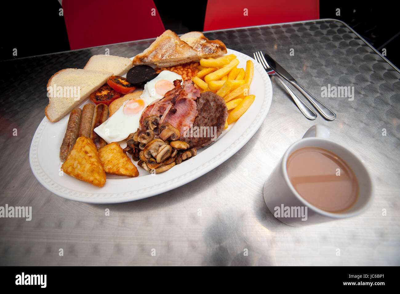 Un petit-déjeuner géant. composé de 2 oeufs, bacon, saucisse 3 3, chips, pommes de terre rissolées, les haricots, tomates, champignons, burger, tranche beurrée, pain grillé. Banque D'Images