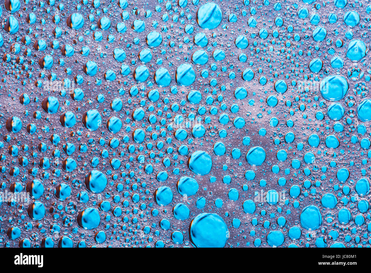 Les gouttes d'eau sur le verre avec la mousse de lave-vaisselle sur fond bleu, abstract wallpaper des pluies Banque D'Images