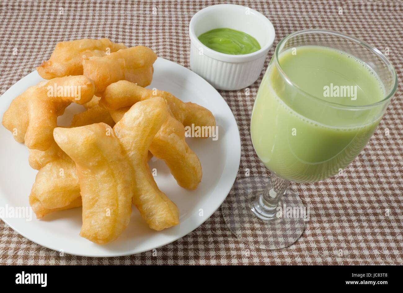 Snack et dessert, des collations traditionnelles chinoises Doughstick Frits sur une plaque blanche Servi avec crème de Pandan Lait de soja vert et Dip. Banque D'Images