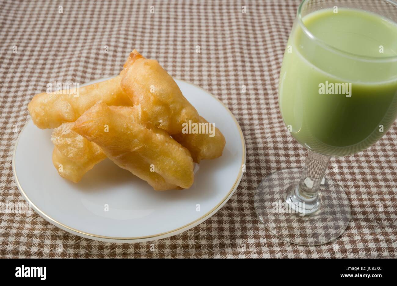 Snack et dessert, des collations traditionnelles chinoises Doughstick Frits sur une plaque blanche servi avec du lait de Soja Thé vert. Banque D'Images