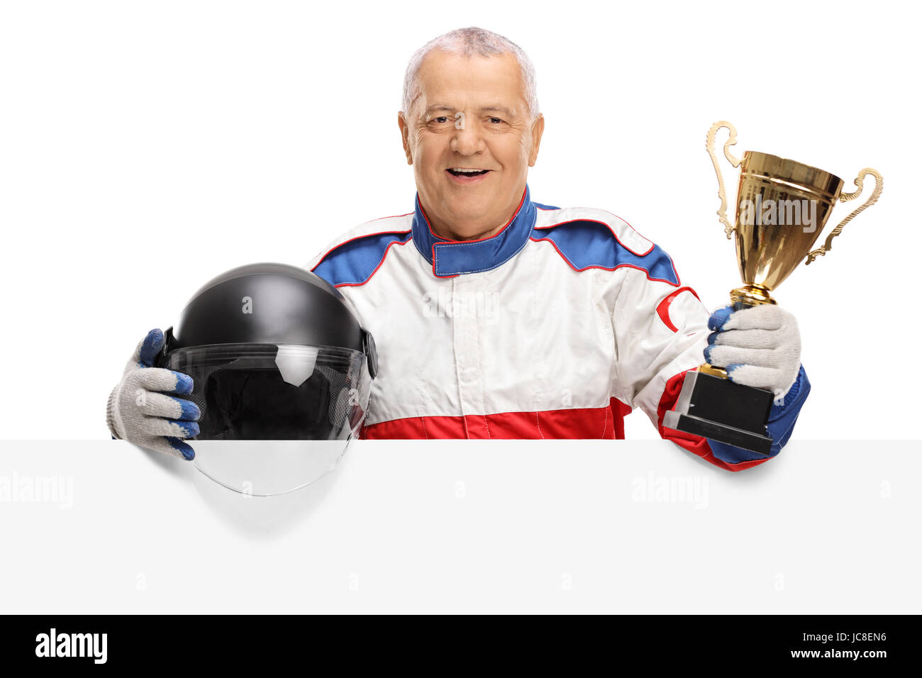 Mature car racer avec un trophée d'or et un casque derrière un panneau isolé sur fond blanc Banque D'Images
