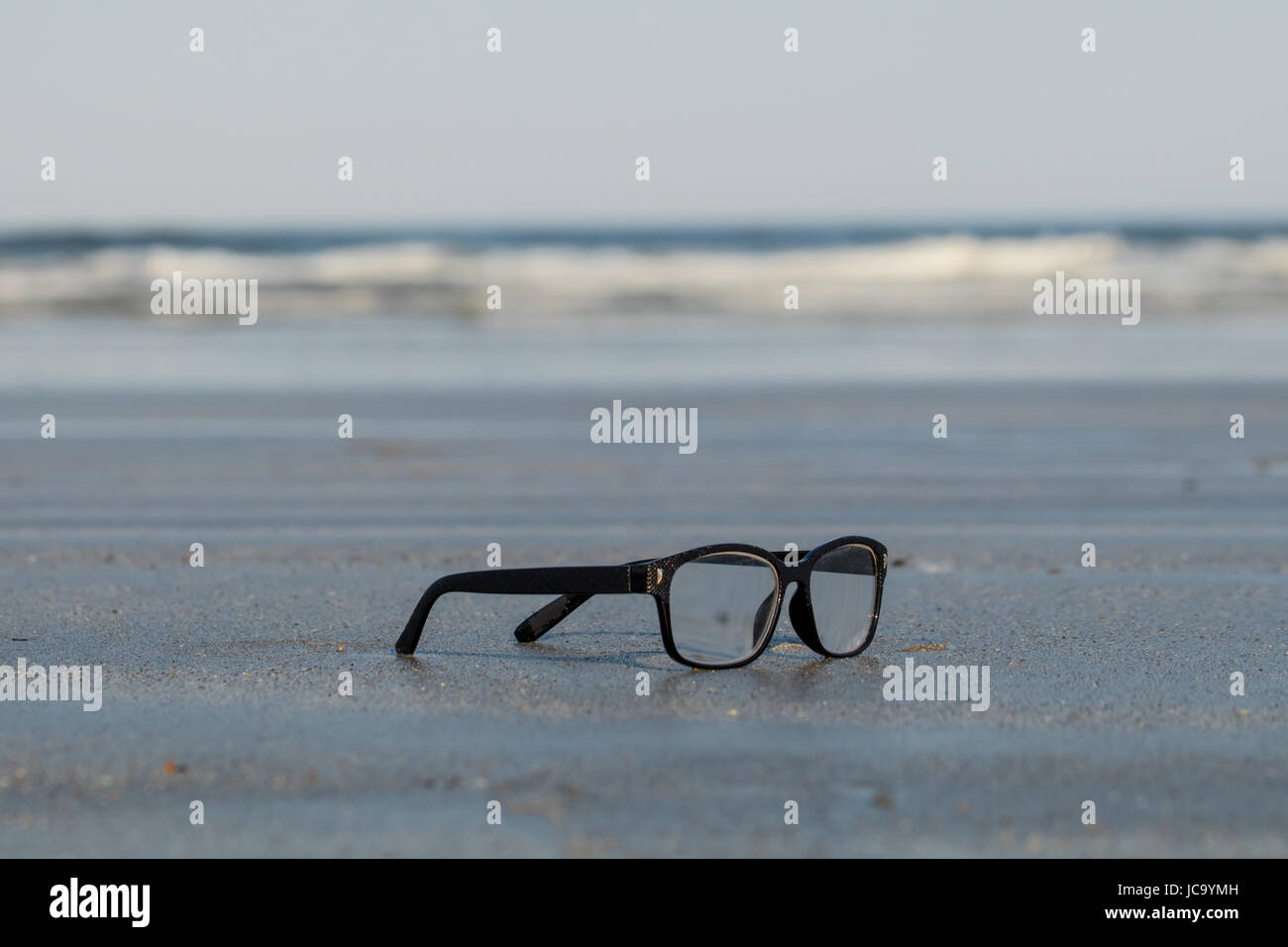 Lunettes perdu sur le sable avec la vague comme arrière-plan Photo Stock -  Alamy