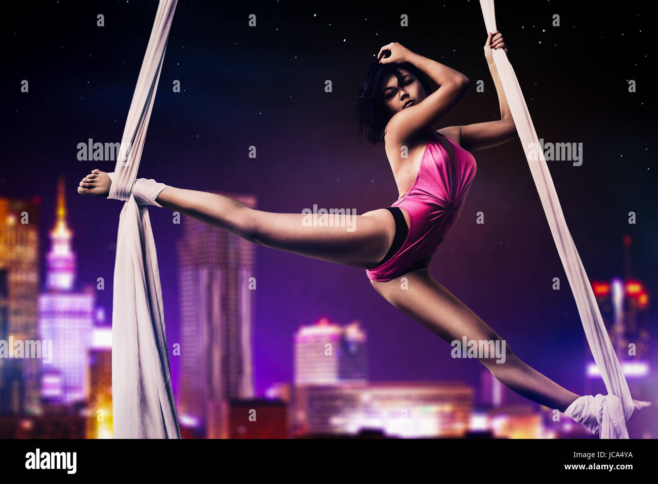 Jeune femme gymnaste sur fond de la ville moderne de nuit Banque D'Images