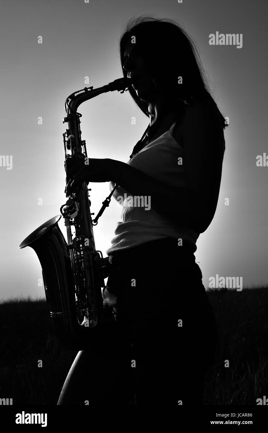 Silhouette d'une femme aux cheveux longs de la lecture d'un saxophone. Photo en noir et blanc Banque D'Images