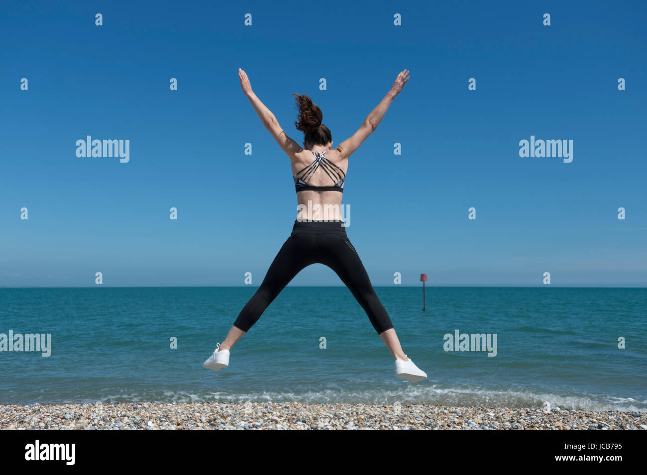 Femme faisant une star jump sur la plage Banque D'Images