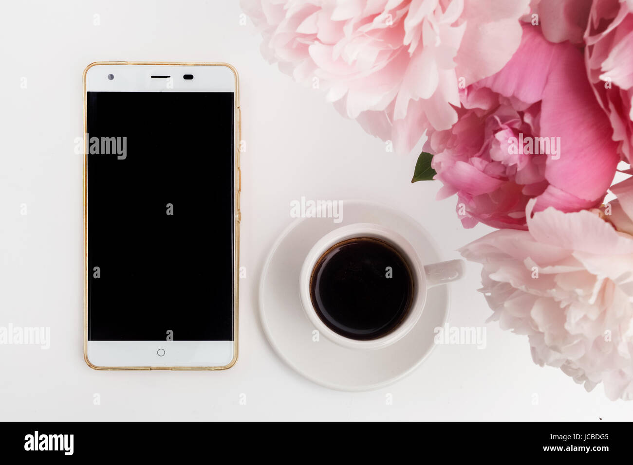 Tasse de café avec téléphone et pivoines sur fond blanc Banque D'Images