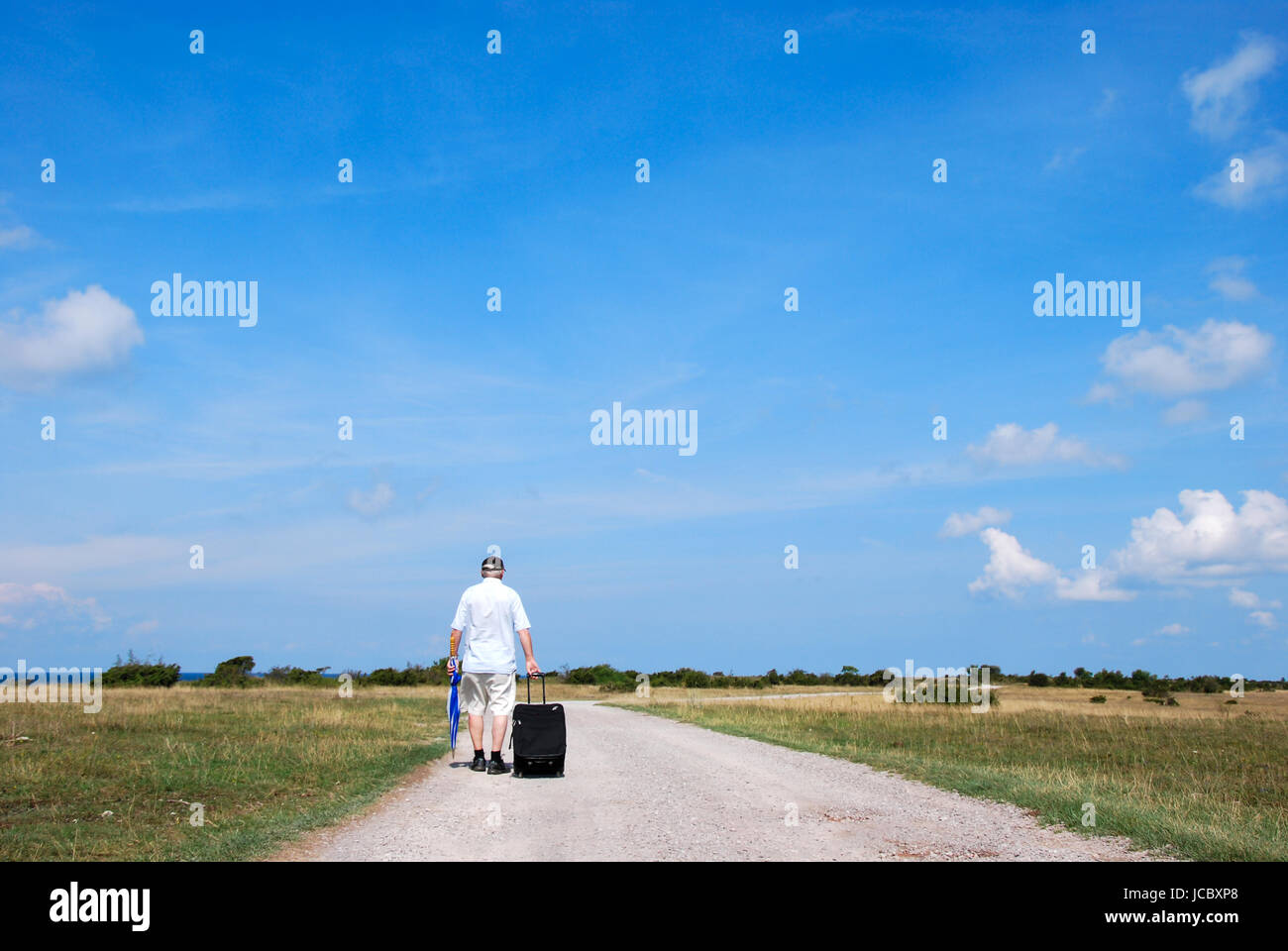 L'homme qui marche avec une valise sur une route de campagne dans un ...