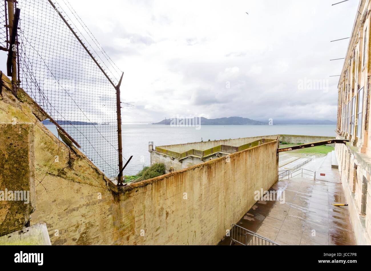 La cour de récréation sur l'île pénitencier d'Alcatraz, maintenant un musée, à San Francisco, Californie, USA. Une vue de la cour d'exercice, la clôture de la prison, le cellhouse, l'île au trésor et le pont de la baie. Banque D'Images