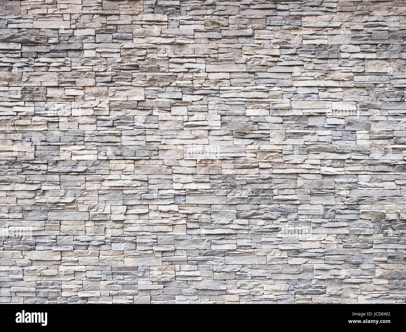 Mur de pierre multicolore structure prévue comme des briques avec des joints de ciment. Banque D'Images