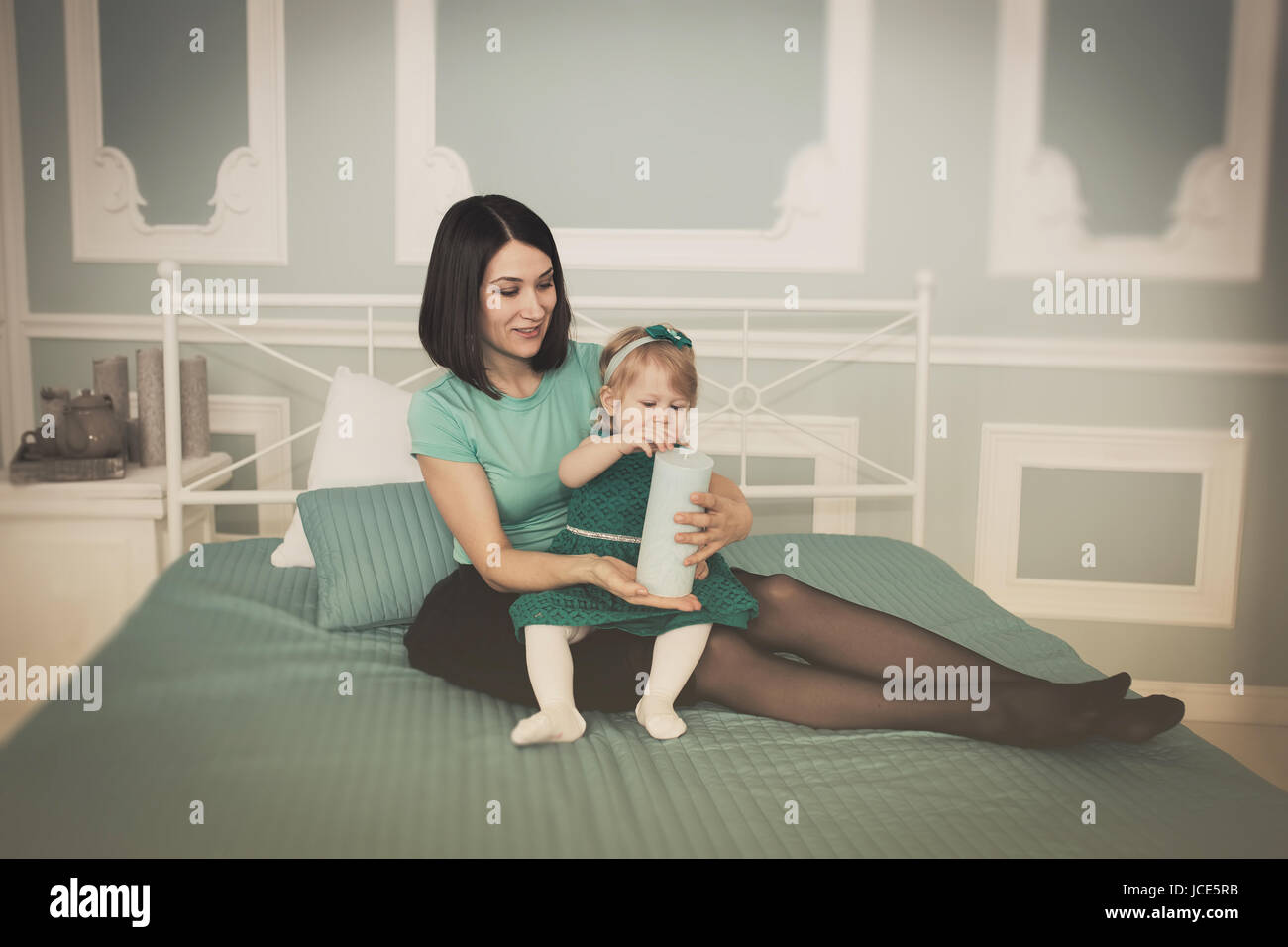 Mère et enfant sur lit jouer avec bougie. Fille et maman choisissez bougie pour party de Noël. Banque D'Images