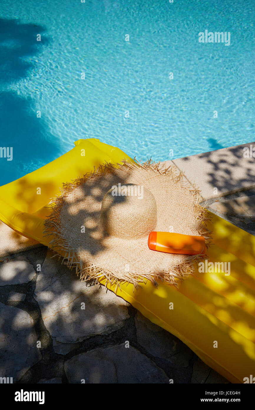 Chapeau et bouteille de crème solaire de la piscine Banque D'Images