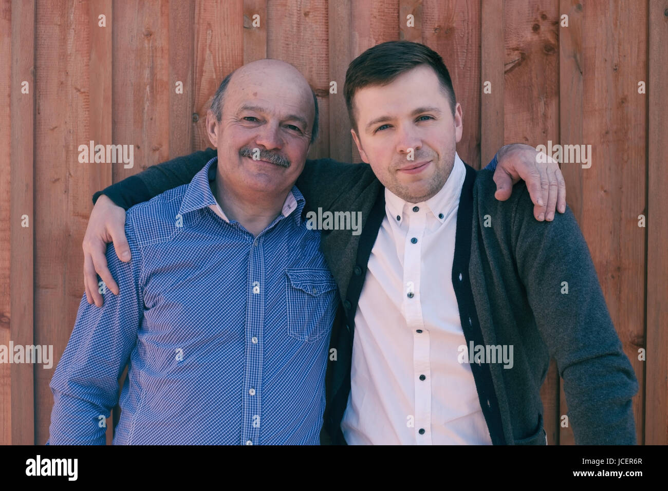 Un père et son fils sur fond de bois. Ils regardent l'appareil photo et sourire heureux. Banque D'Images