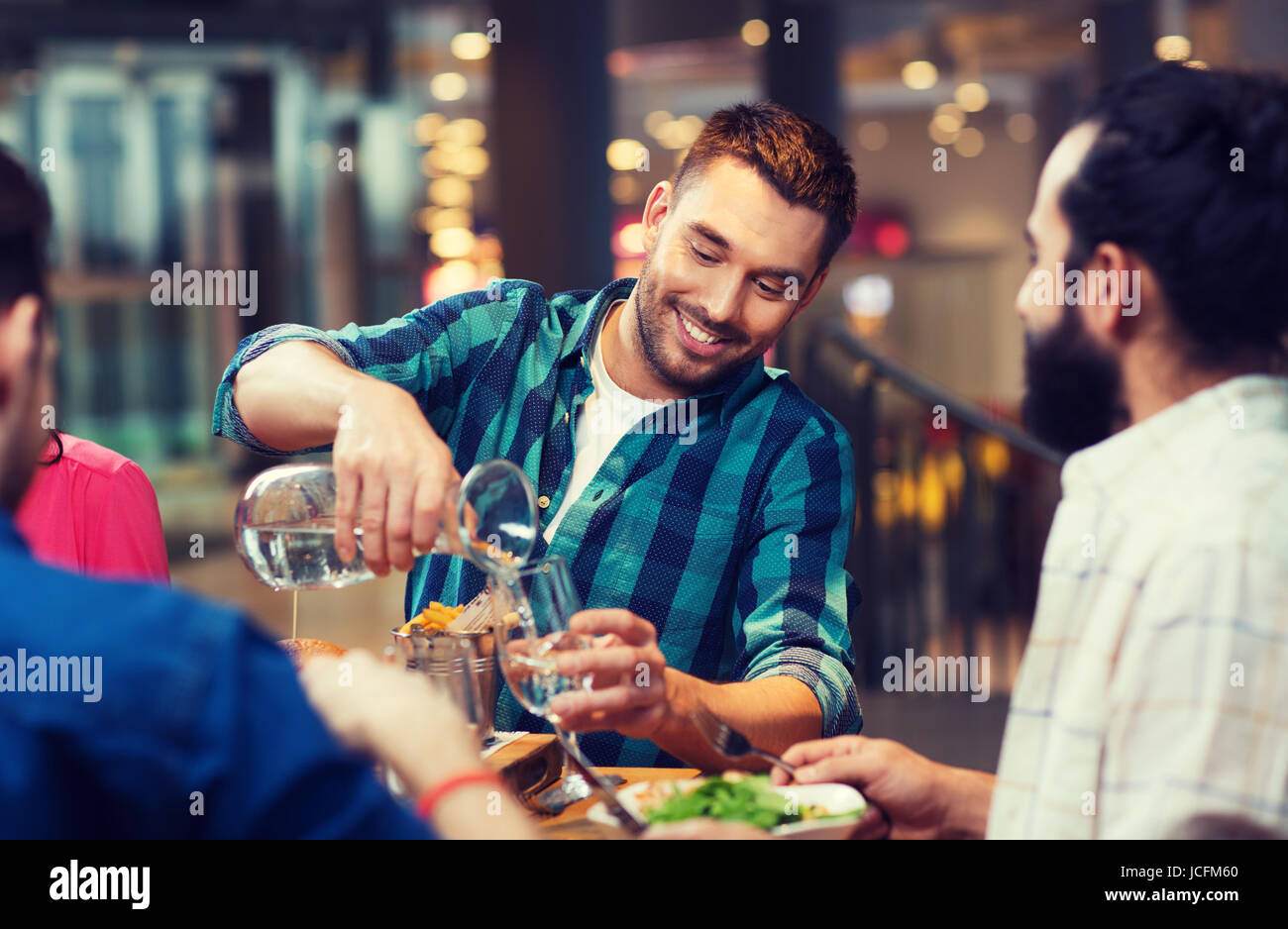 Homme heureux avec vos amis verser de l'eau at restaurant Banque D'Images