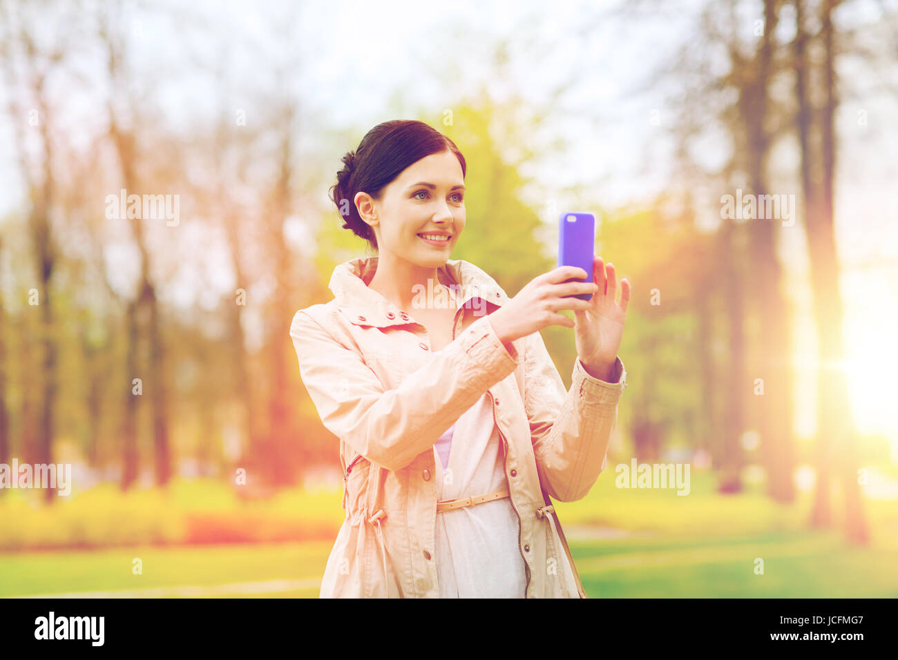 Smiling woman taking picture with smartphone Banque D'Images