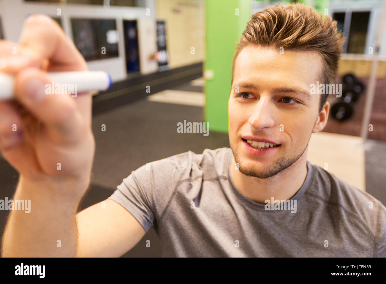 Heureux jeune homme avec le marqueur écrit in gym Banque D'Images