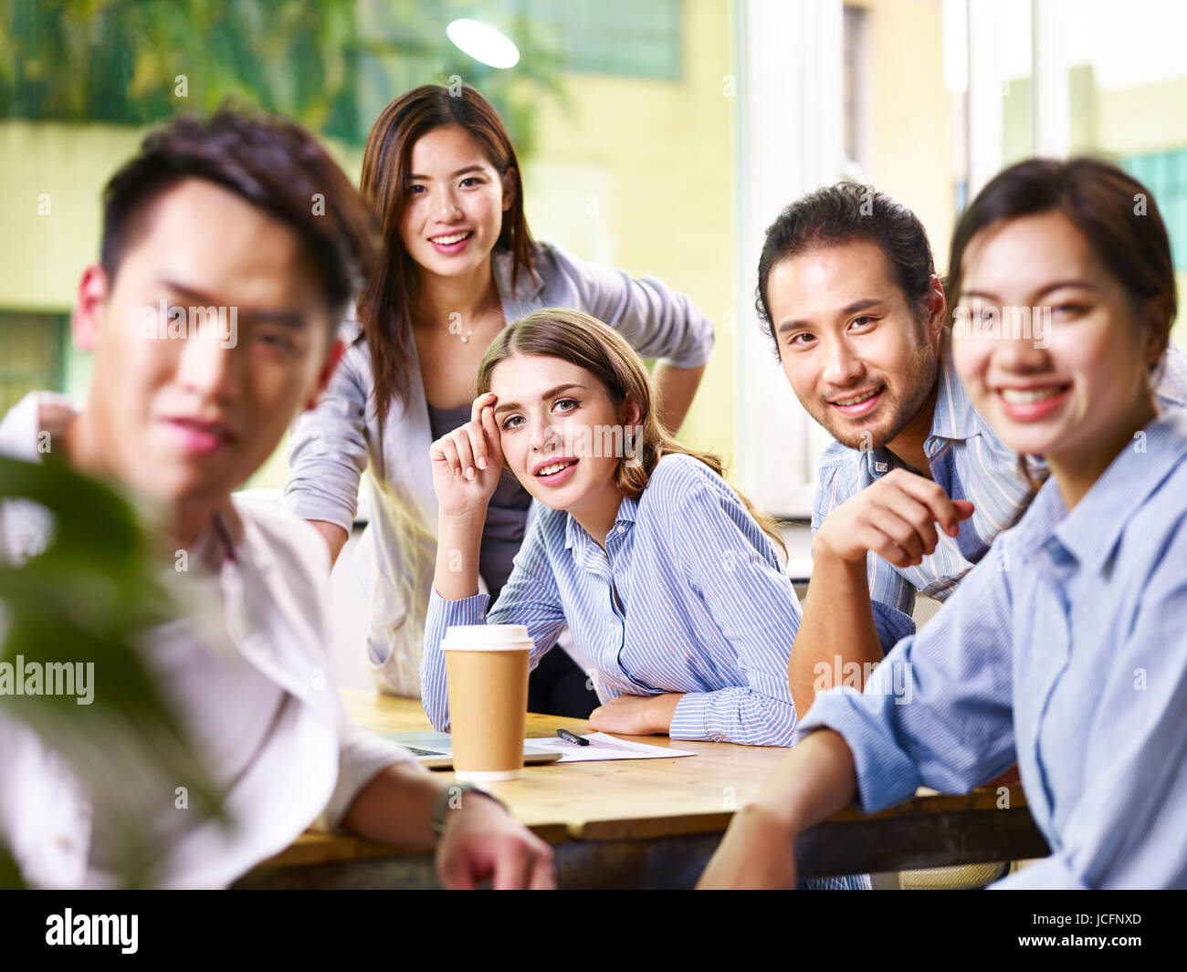 Une équipe d'affaires asiatique et caucasienne smiling at camera au cours de réunions d'affaires. Banque D'Images