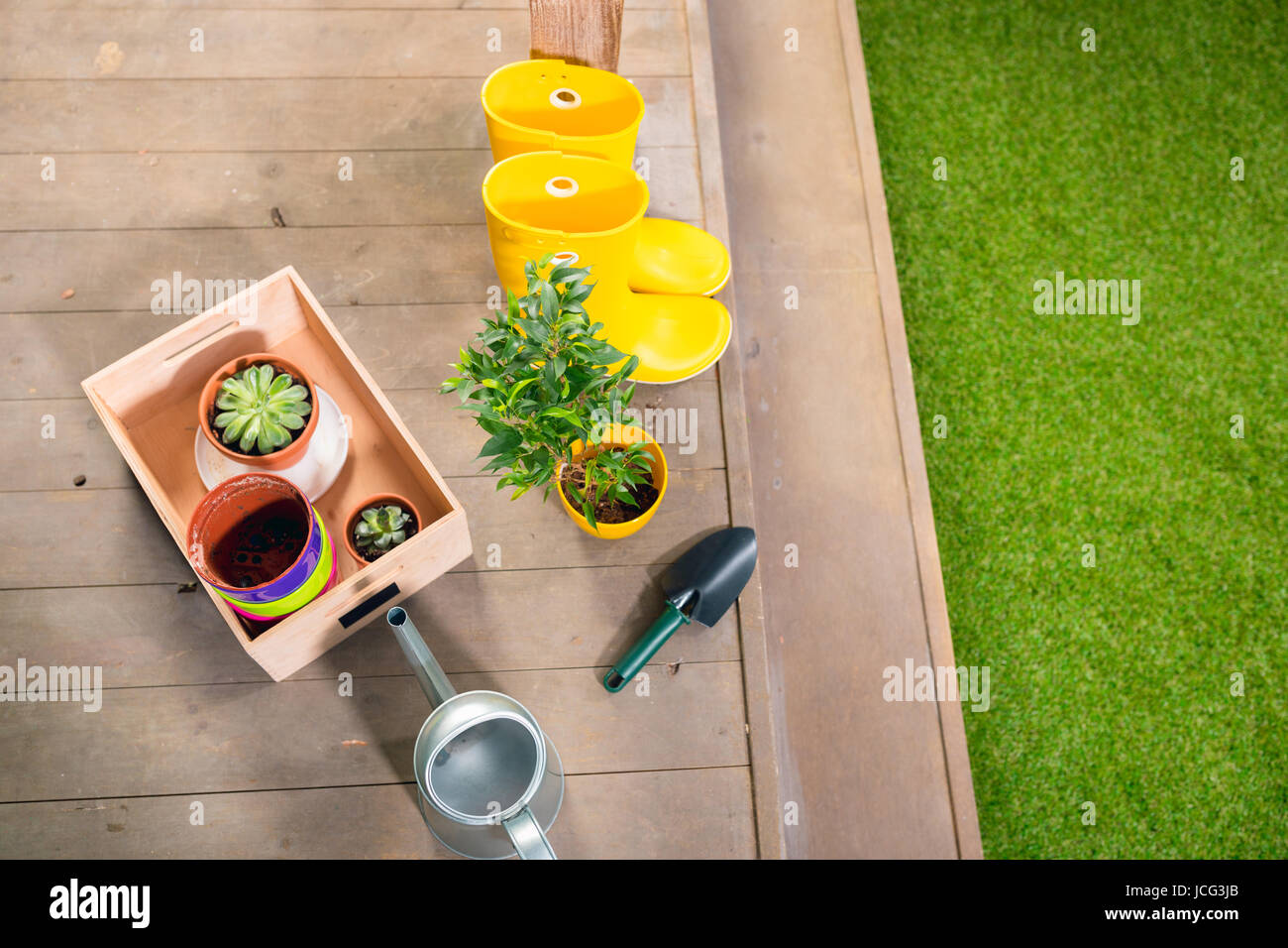 Arrosoir, bottes jaunes et de plantes, dans un coffret en bois on porch Banque D'Images