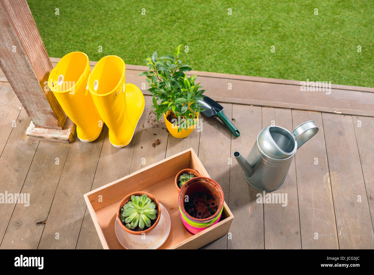Arrosoir, bottes jaunes et de plantes, dans un coffret en bois on porch Banque D'Images