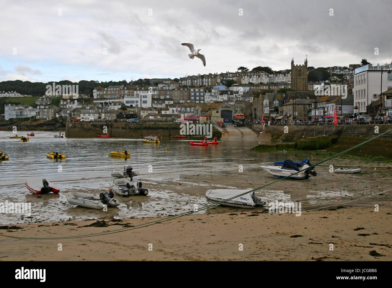 Approches tempête St Ives harbour Cornwall. Un oiseau vole et bateaux sont amarrés à marée montante, comme avec ciel bleu à distance derrière les nuages gris et blanc Banque D'Images