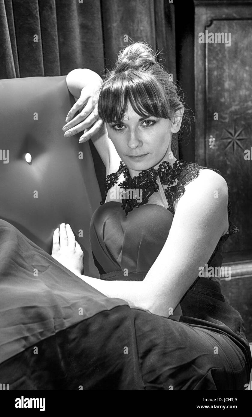 Portrait de femme assise sur le siège rouge. Sosie d'Audrey Hepburn. Banque D'Images