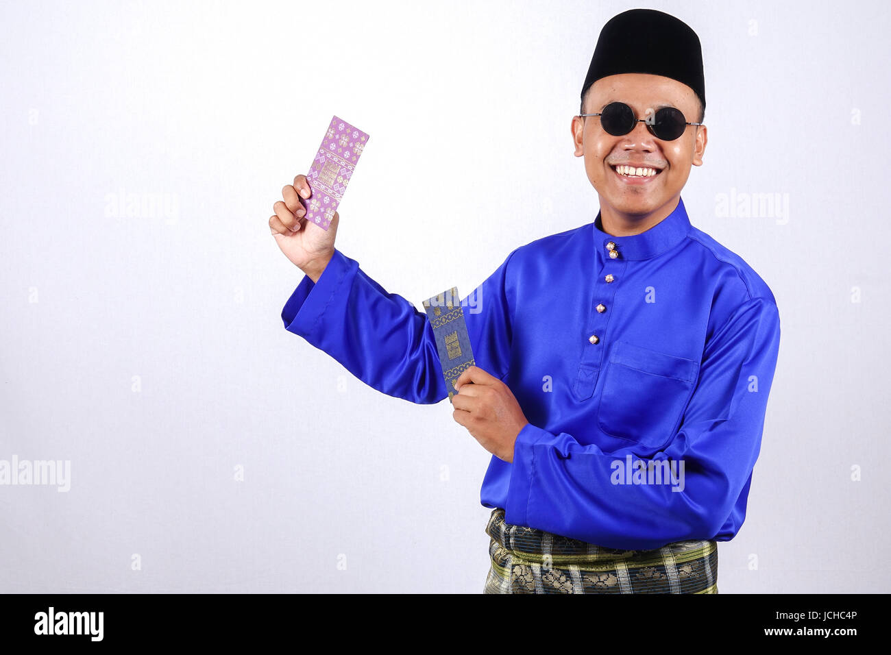 L'homme en costume traditionnel de bonne humeur avec paquet d'argent au cours de célébrer l'aïd Fitr. Banque D'Images