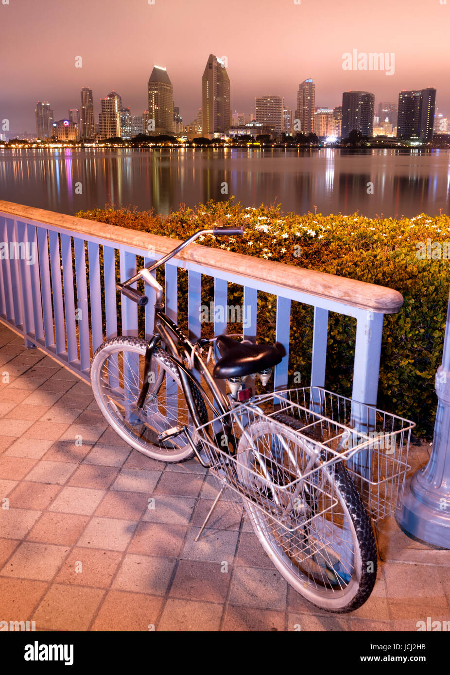 Un vélo est verrouillé à la clôture à Coronado à San Diego dans l'arrière-plan dans la nuit Banque D'Images Un vélo est verrouillé à la clôture à Coronado à San Diego dans l'arrière-plan dans la nuit Banque D'Images
