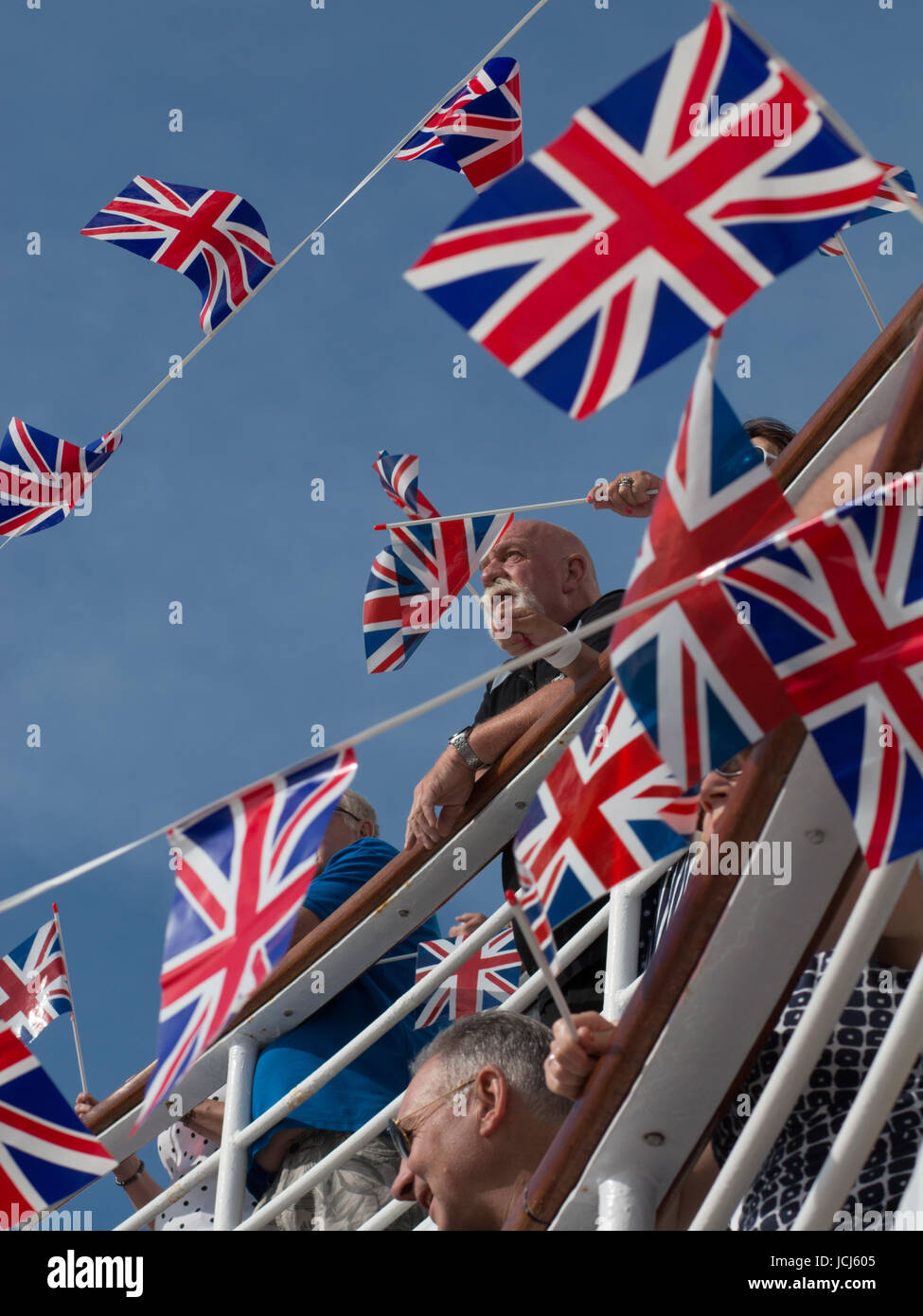 Les passagers de croisière à un parti sailaway entouré de drapeaux Union Jack. Quelques drapeaux sont en cours d'agité. Il y a un ciel bleu clair. Banque D'Images