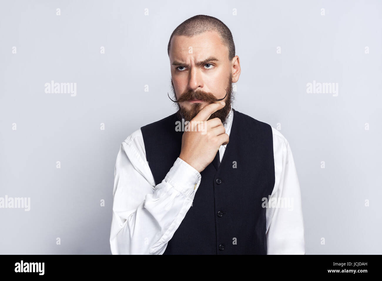 La pensée. Handsome businessman avec barbe et moustache à la pensée et guidon. studio shot, sur fond gris. Banque D'Images