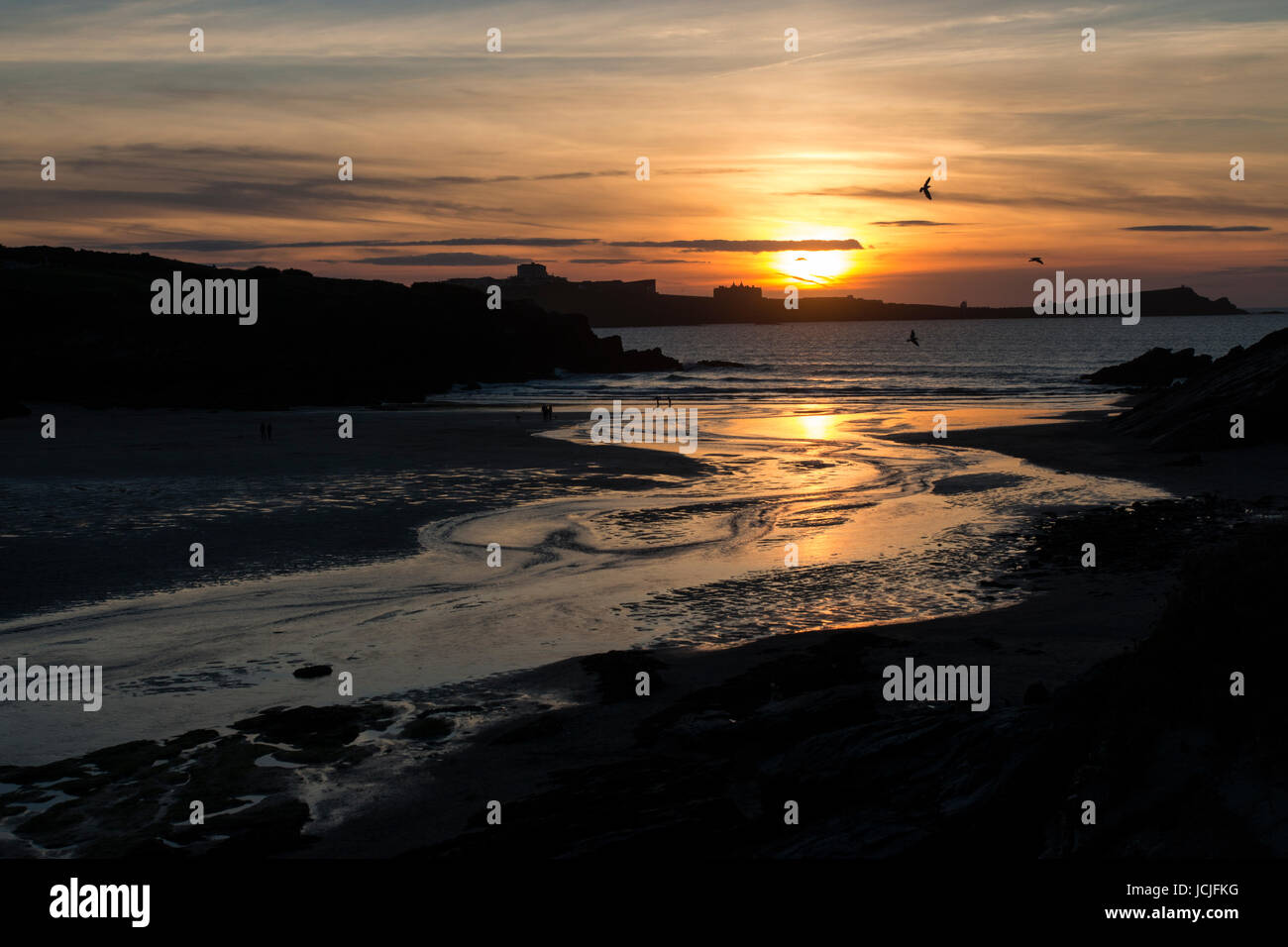 Coucher du soleil doré avec des réflexions sur la plage de Porth et plage de Towan avec pointe Hotel à distance Banque D'Images