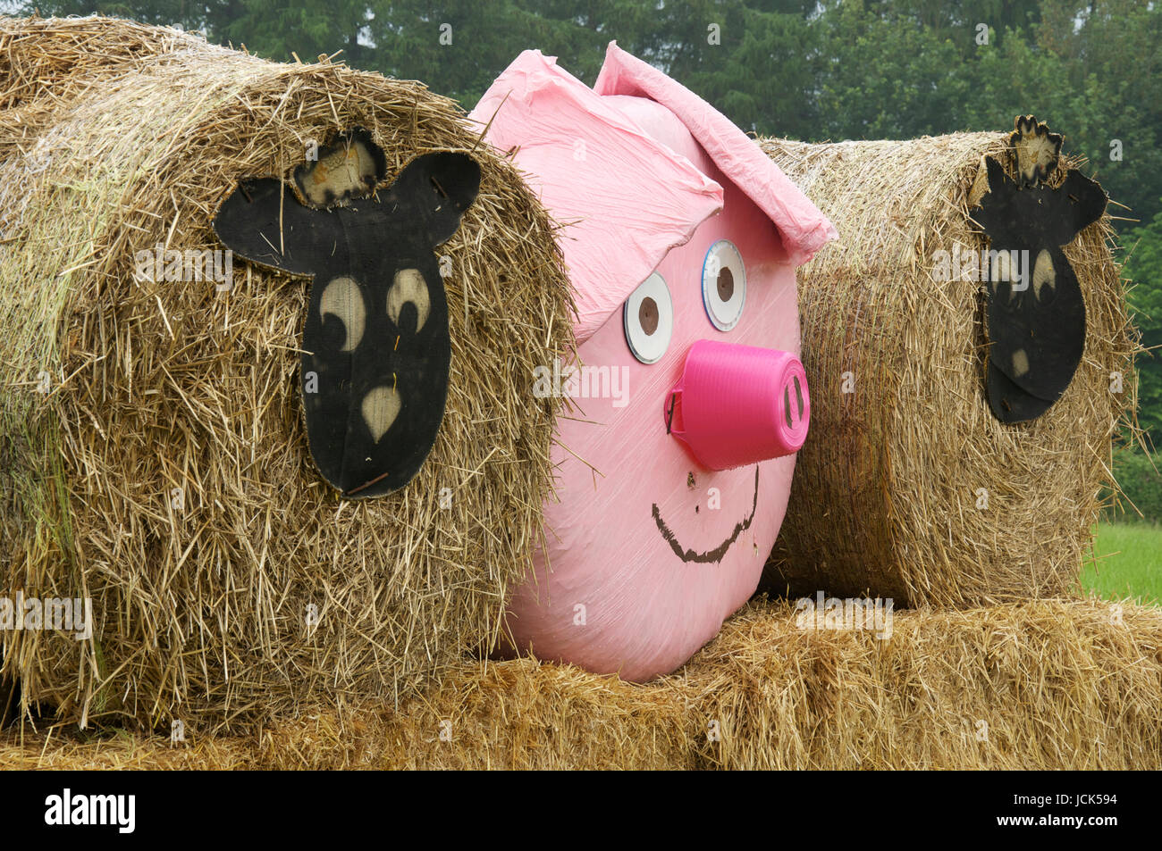 Animaux à bande dessinée représentant des moutons et un cochon rose décorer trois balles de foin disposés dans un champ près de Dorchester. Dorset, Angleterre, Royaume-Uni. Banque D'Images