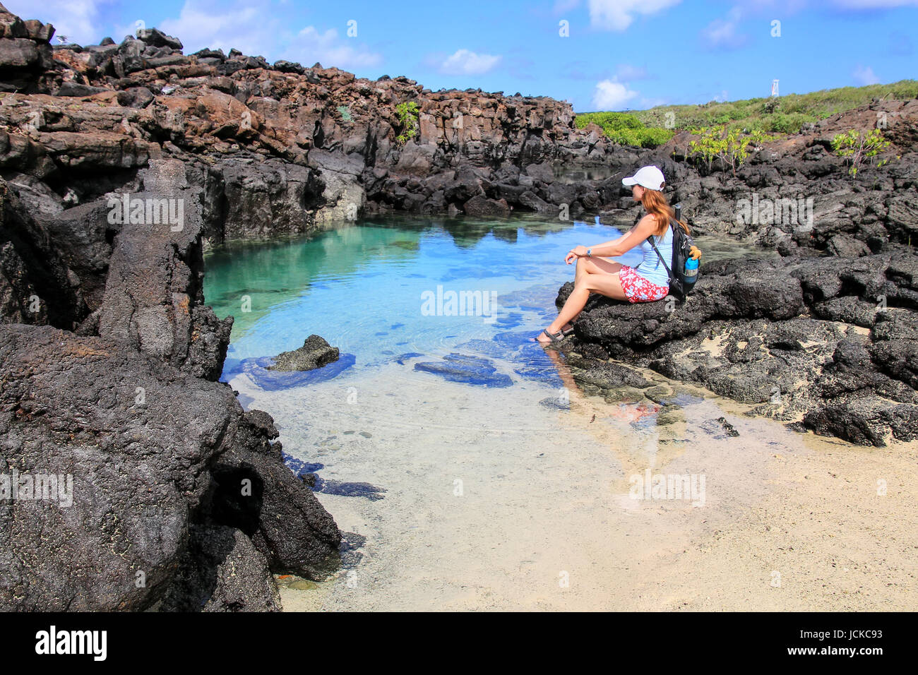 Jeune femme se reposant près de petite lagune à l'eau claire, de l'île de Genovesa au Parc National des Galapagos, Equateur Banque D'Images