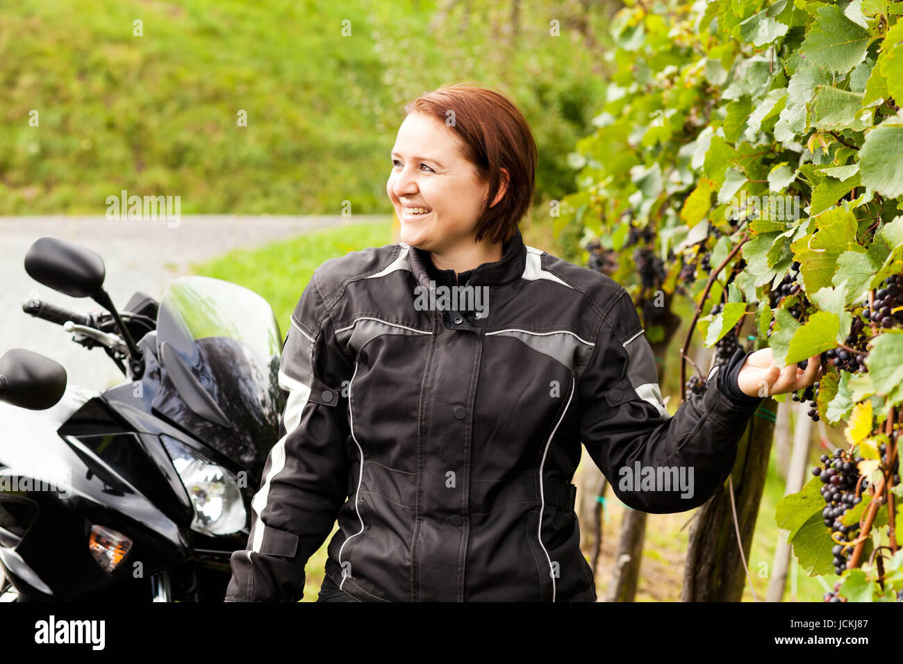 Motorradfahrerin pflückt Weintrauben Banque D'Images