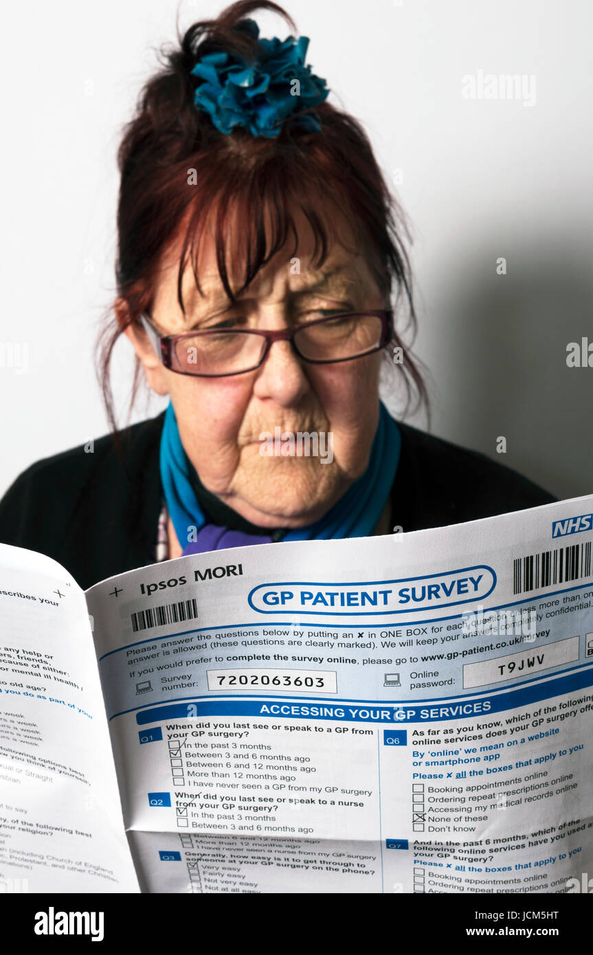 Femme âgée lisant NHS Patient GP Formulaire d'enquête Banque D'Images