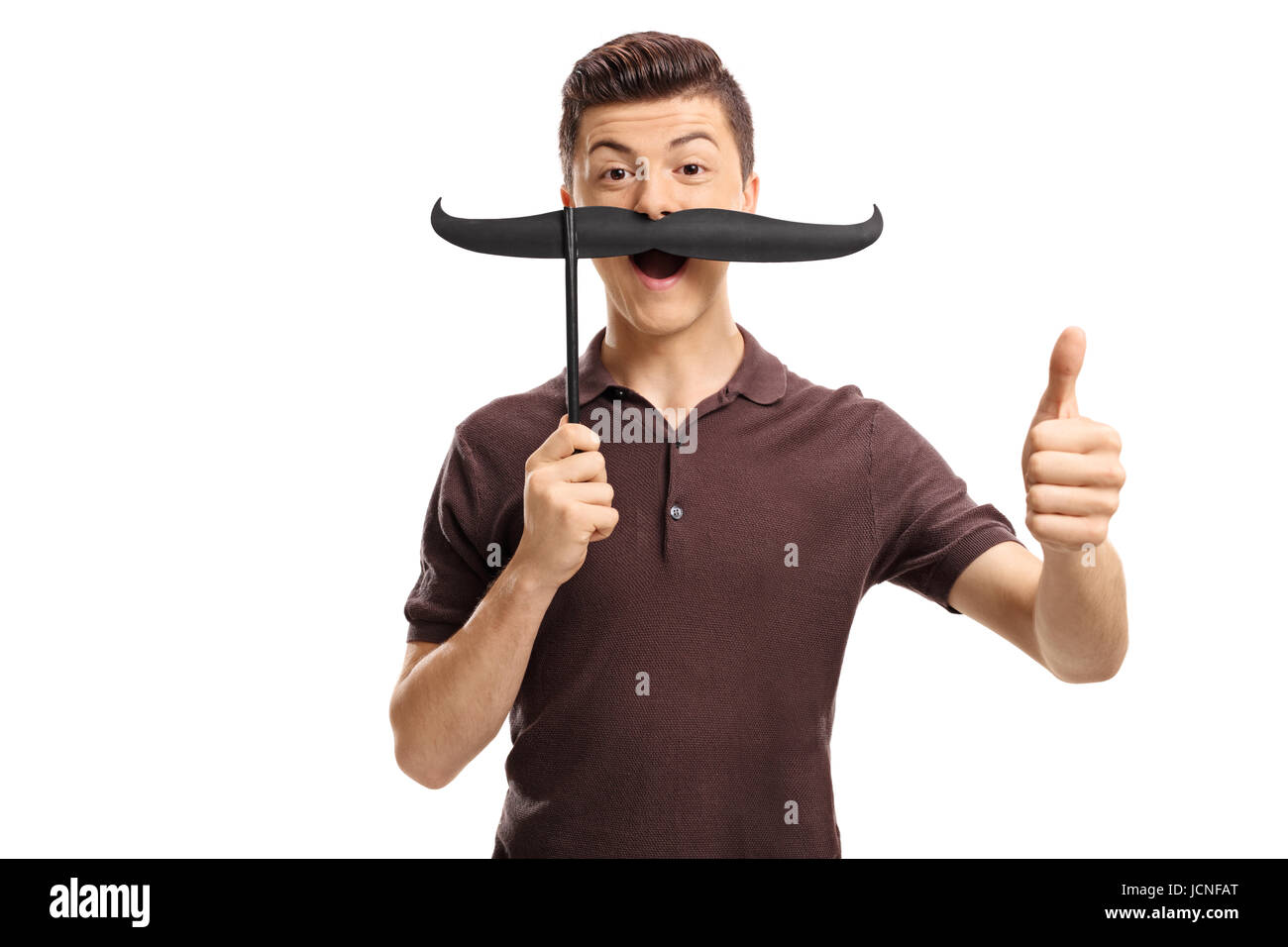 Teenage boy with fake moustache faisant un geste vers le pouce isolé sur fond blanc Banque D'Images