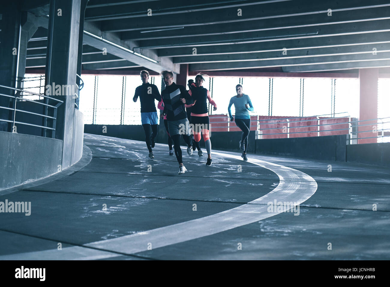 Les jeunes adultes en formation sportive sport en salle de sport et s'exécutant sur la piste de course contre la fenêtre. Banque D'Images