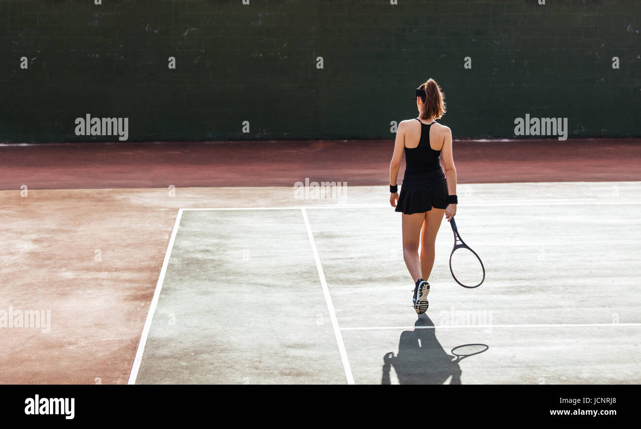 Vue arrière pleine longueur de la joueuse de tennis sur le court. femme sportive jouant sur un court de tennis. Banque D'Images