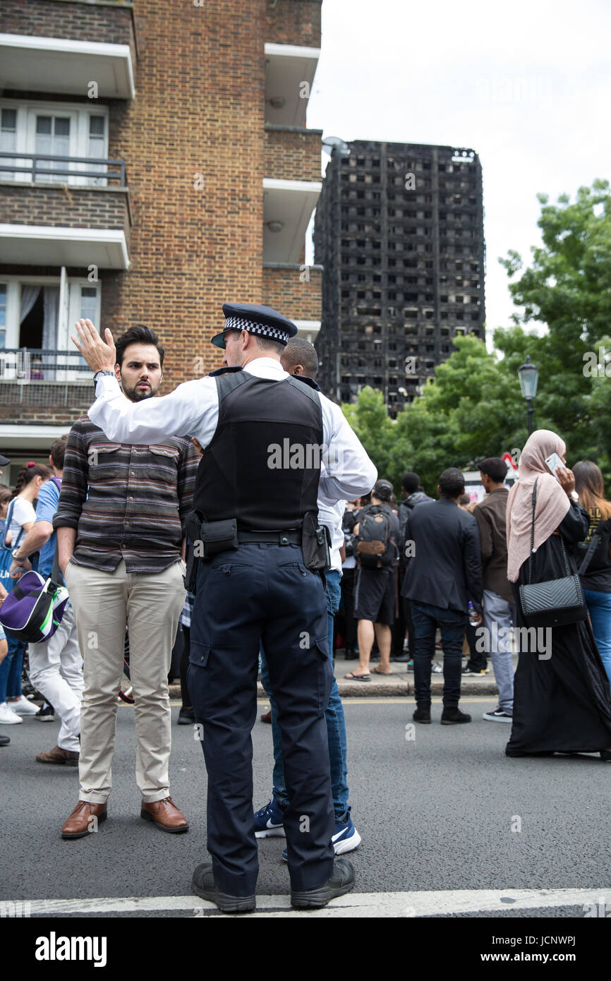 Londres, Royaume-Uni. 16 Juin, 2017. Un agent de police dirige les membres du public à Bramley Road en face de la carcasse brûlée de la tour de Grenfell. Credit : Mark Kerrison/Alamy Live News Banque D'Images