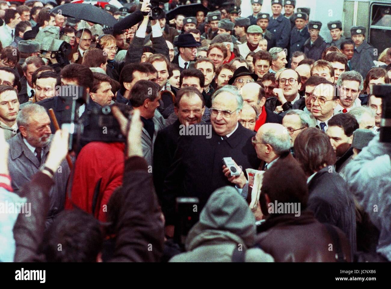 (Afp) - (L-R) Berlin est maire Erhard Krack, le Chancelier Helmut Kohl, l'ouest de Berlin le maire Walter Momper et le ministre des Affaires étrangères, Hans-Dietrich Genscher font leur chemin à travers une foule de gens devant la porte de Brandebourg, Berlin, 22 décembre 1989. 28 ans après le mur a été érigé, les transitions ont été ouvertes et les gens pouvaient passer la porte. Dans le monde d'utilisation | Banque D'Images