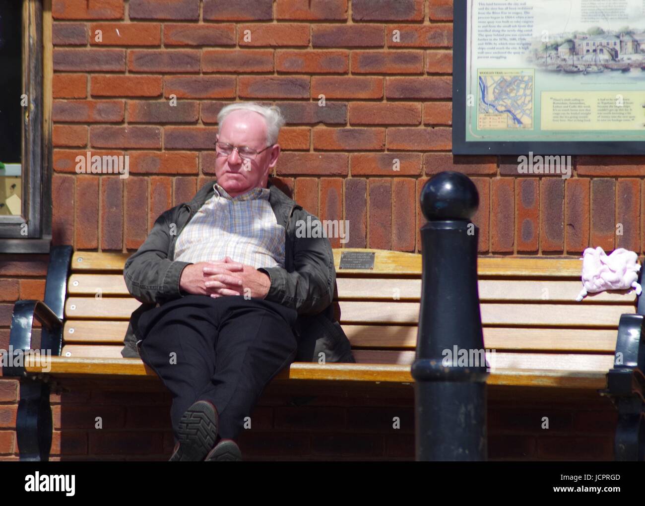 Un vieux monsieur somnole au large sur un banc à Exeter Quay. Devon, Royaume-Uni. Juin, 2017. Banque D'Images