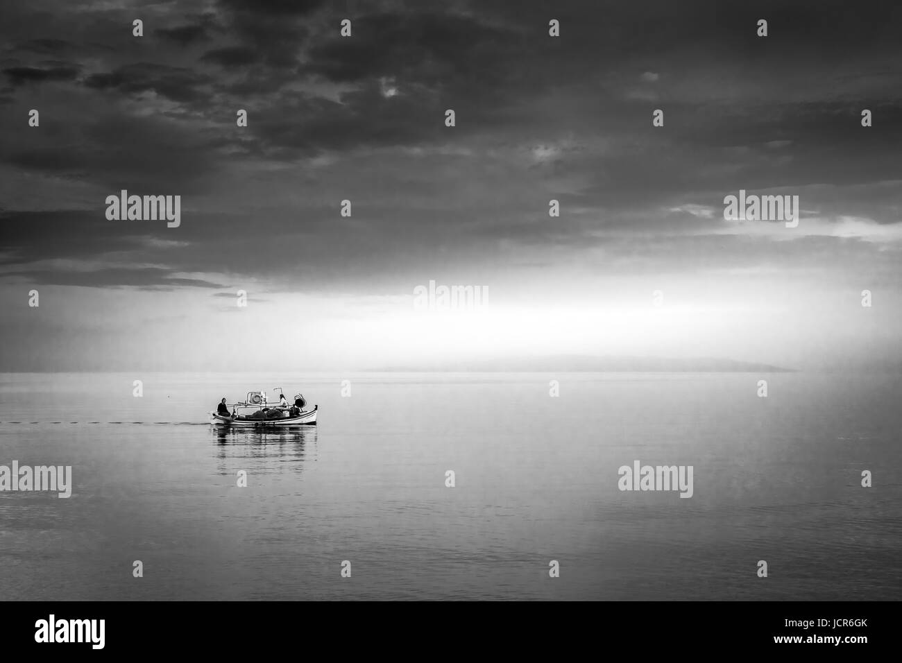 Un petit bateau de pêche naviguant dans les eaux calmes, juste avant la tombée de la nuit. Banque D'Images