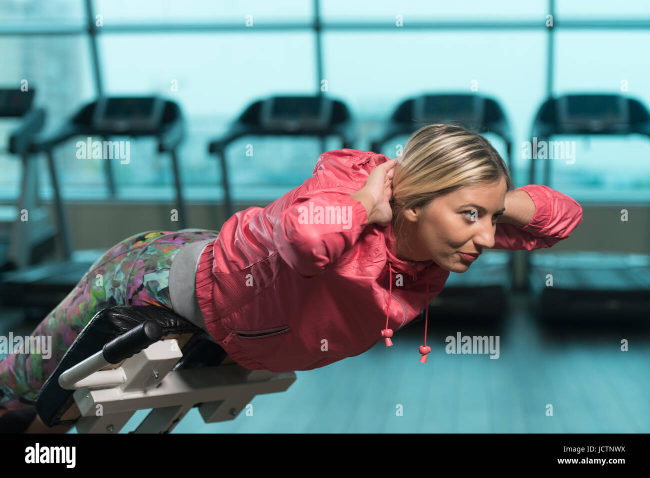 Young Woman Working Out Remise en Forme Retour sur chaise romaine au centre de remise en forme Banque D'Images