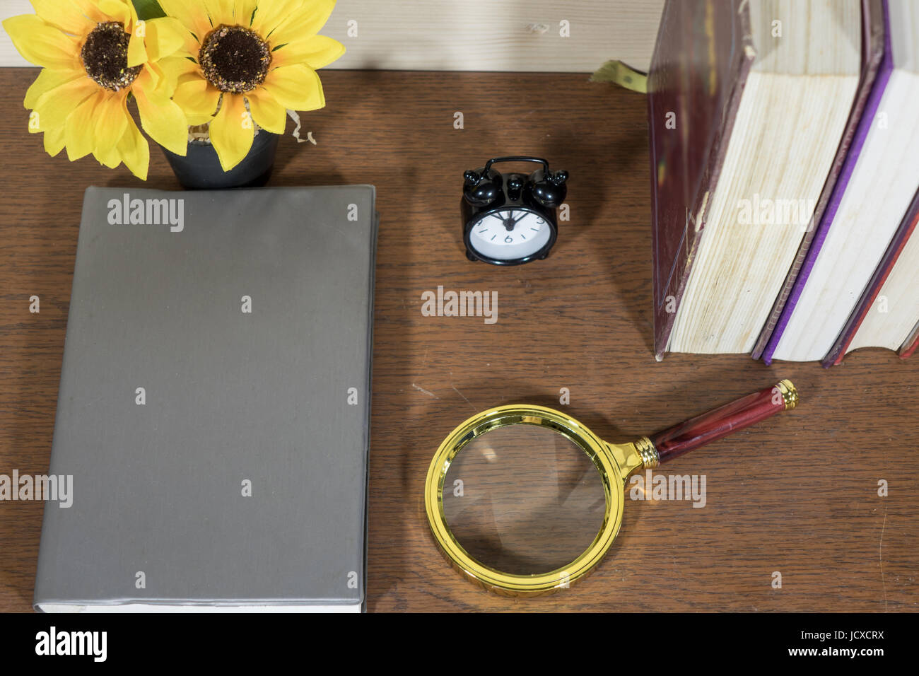 Livre fleurs loupe et horloge sur le plancher de bois. Banque D'Images